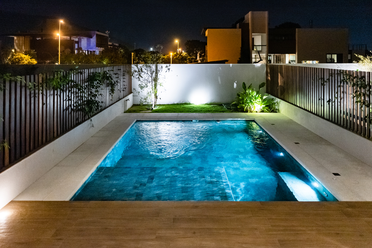 Modern plunge pool with ambient night lighting in a small backyard.