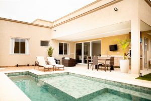 Small backyard pool with lounge chairs and outdoor dining area. Title: Cozy backyard pool with seating and dining space.