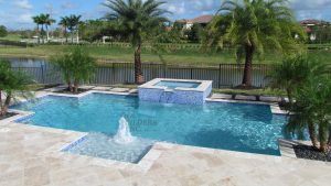 Freeform swimming pool with raised spa, palm landscaping, and water feature by Pool Builders Inc. in South Florida