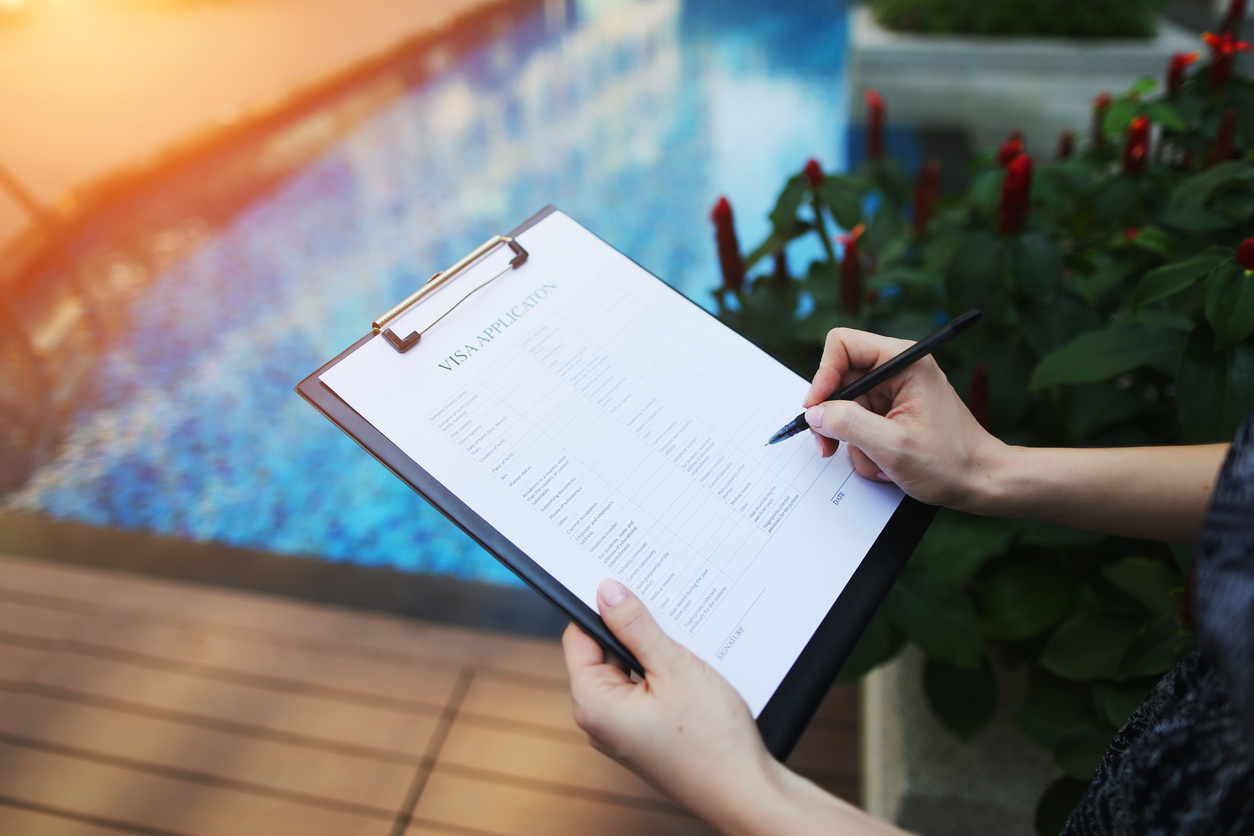 Homeowner filling out pool permit paperwork by a backyard pool, representing pool permits and regulations in Davie, FL